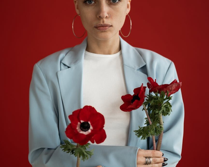 serious woman standing with red poppies in hands and looking at camera