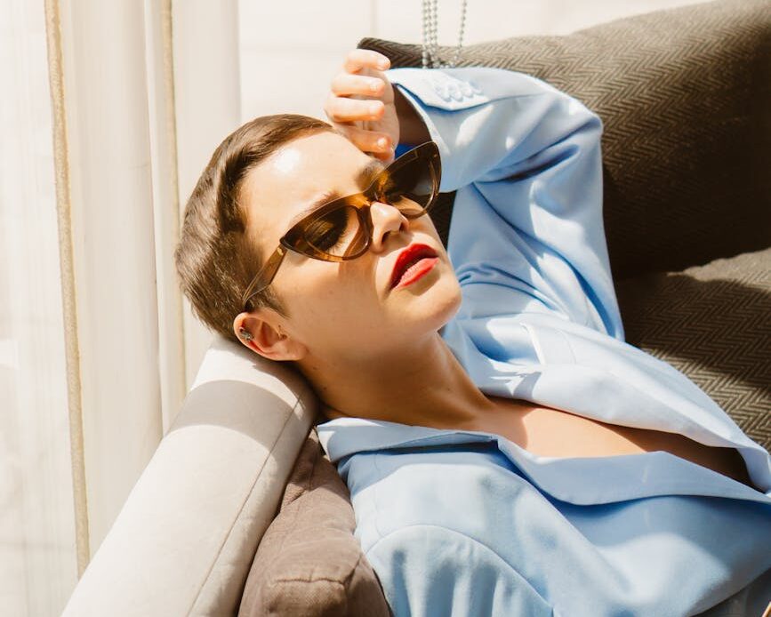 woman in sunglasses and shirt lying down on couch