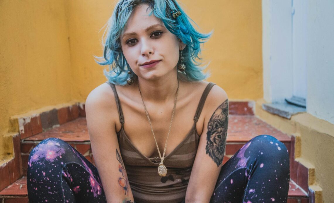 a woman with blue hair sitting on steps