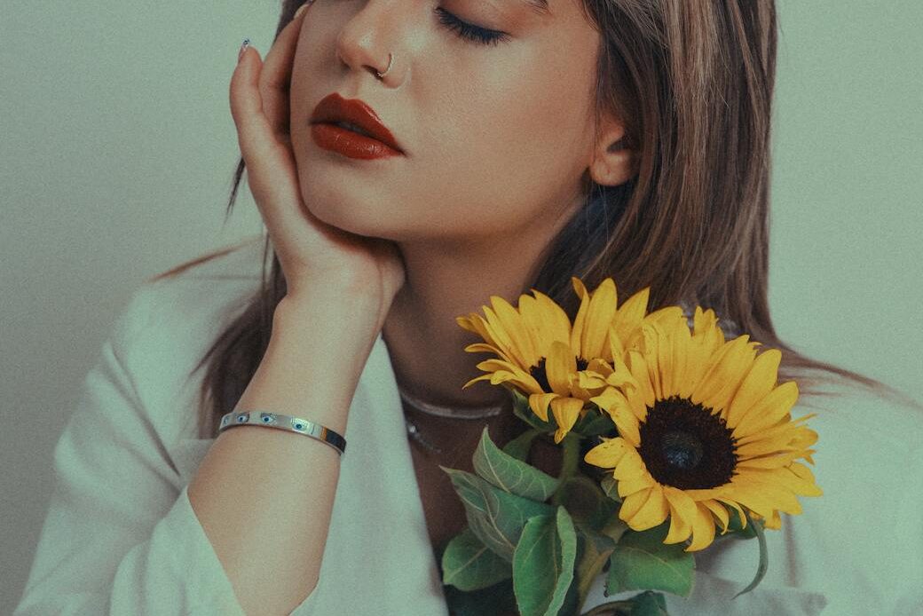 a model in a white shirt is holding a sunflower