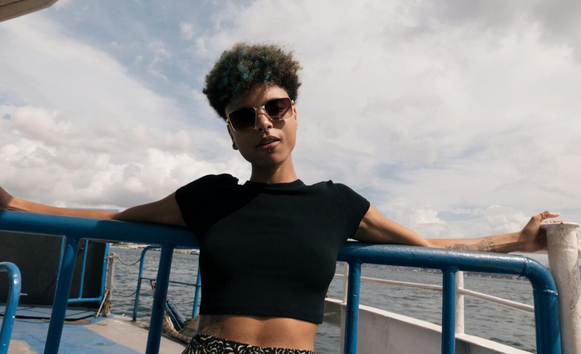 a woman with short hair and a black crop top is sitting on a boat