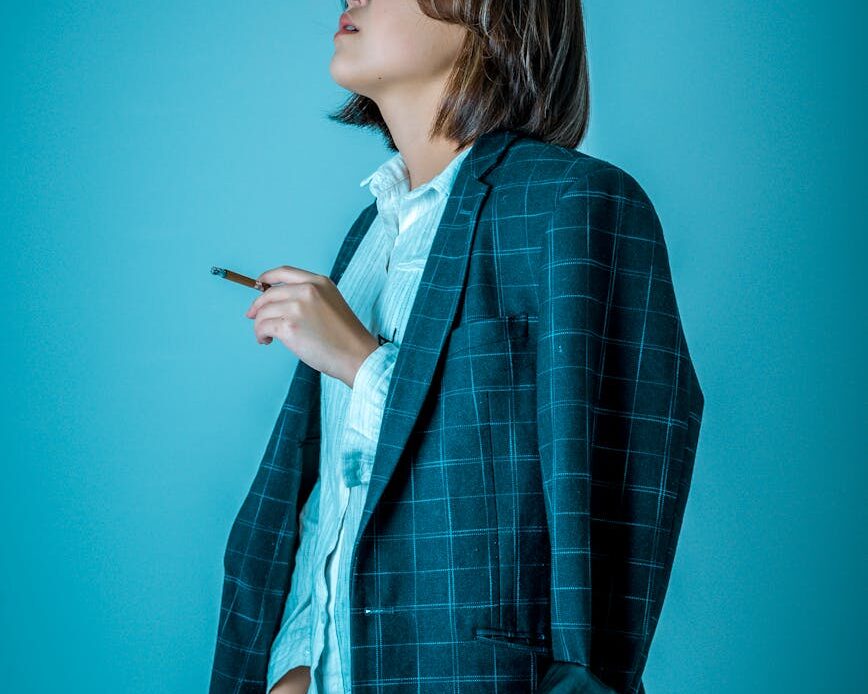 woman wearing blazer while standing against blue background