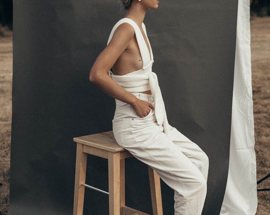 stylish woman sitting near gray textile