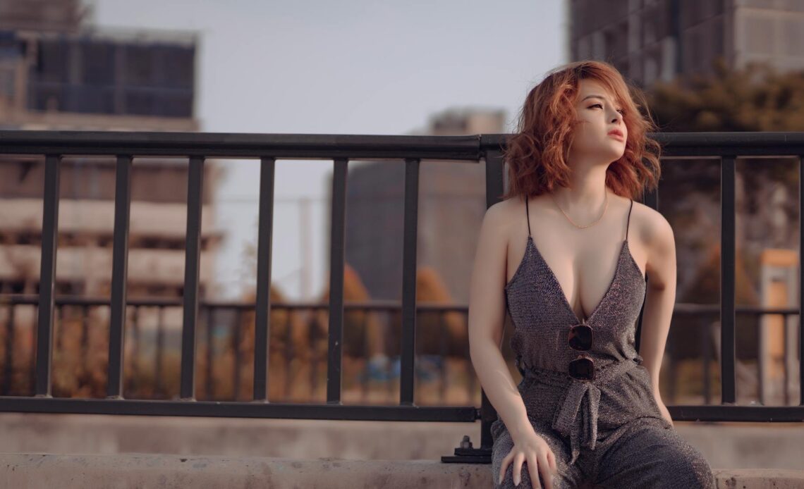 gorgeous female in stylish outfit sitting on stone fence