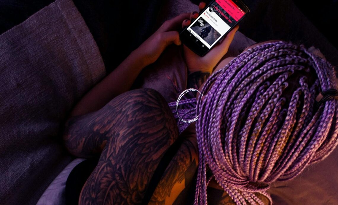 woman with purple braided hair holding an android smartphone