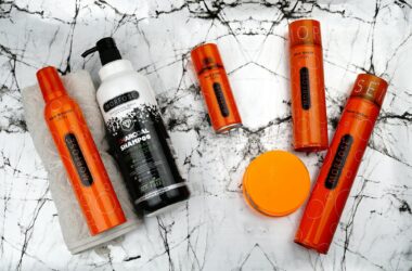 a collection of orange and black hair products on a marble surface