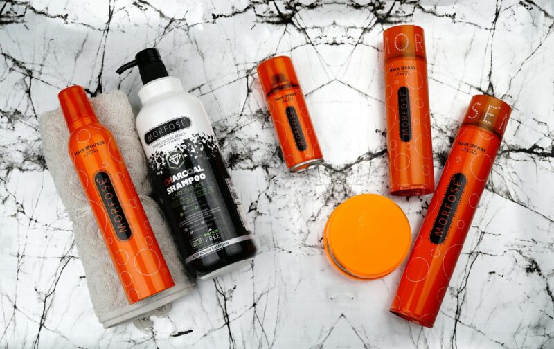 a collection of orange and black hair products on a marble surface