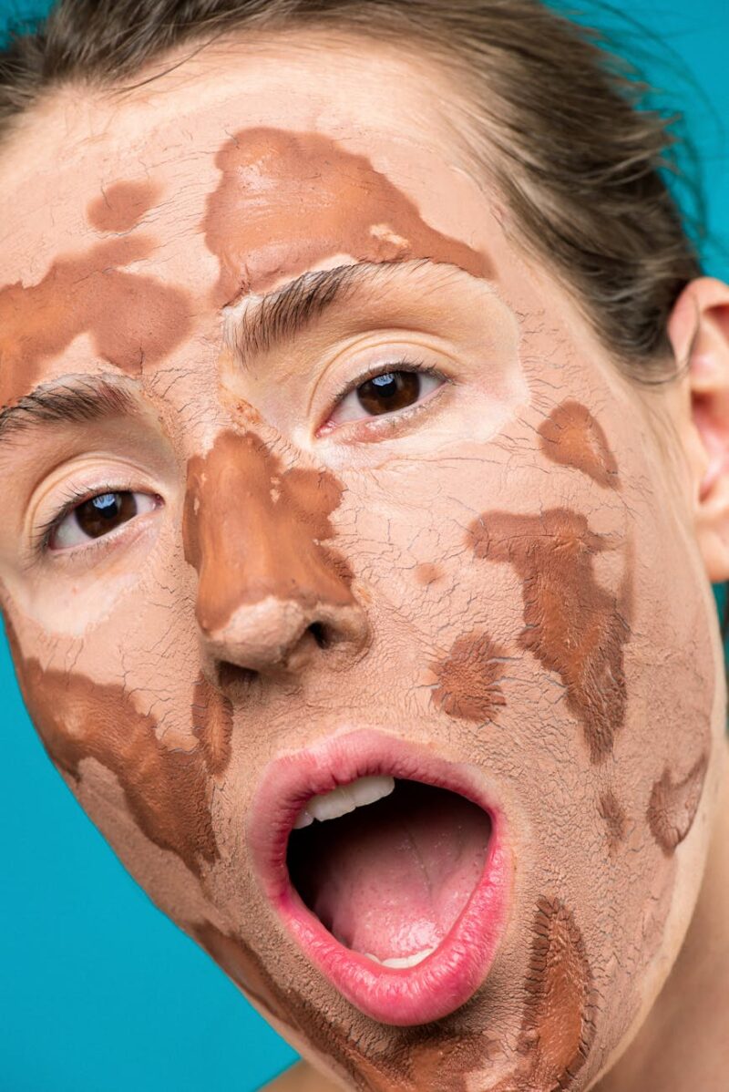 person with clay mask on her face