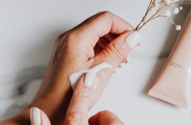 person holding white flower while applying lotion