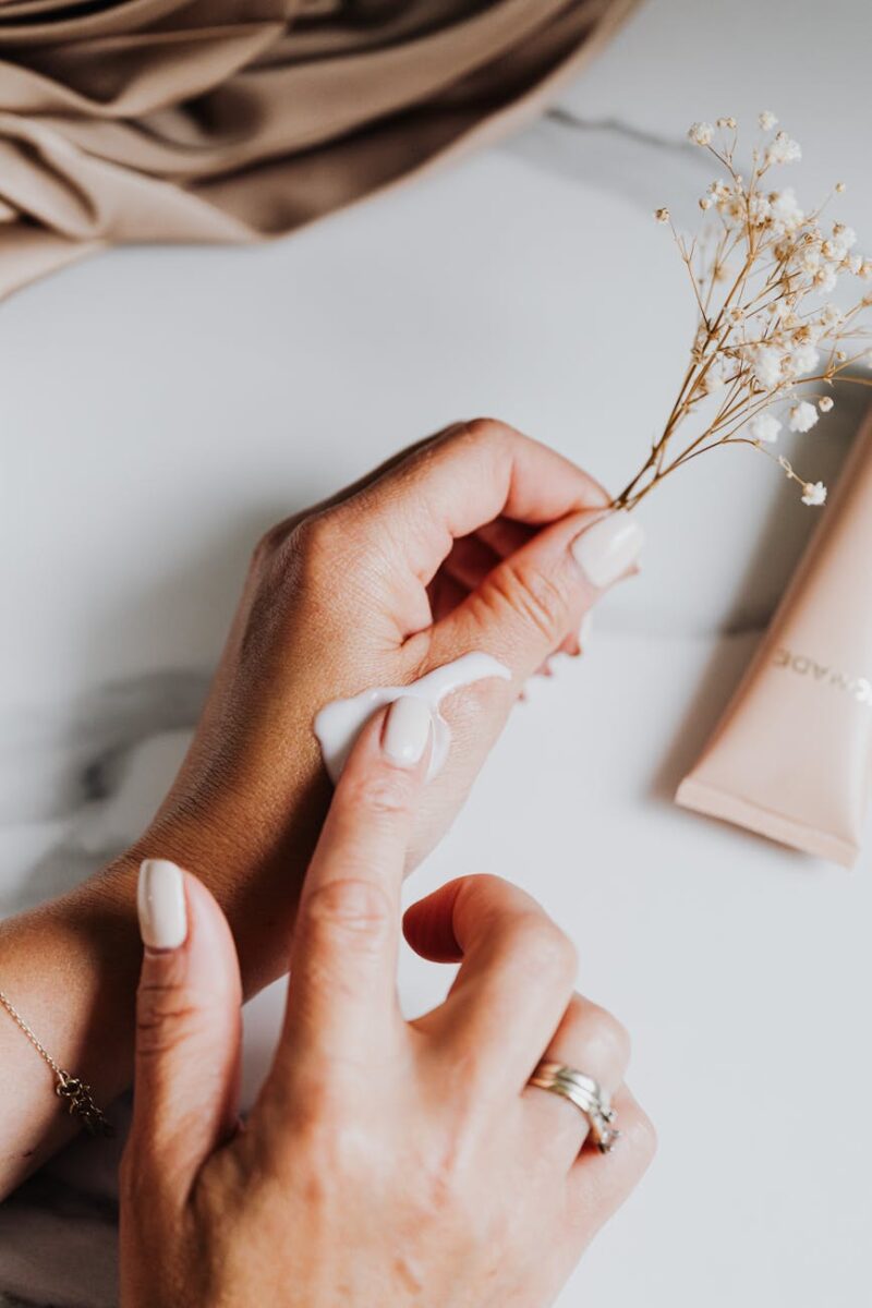 person holding white flower while applying lotion