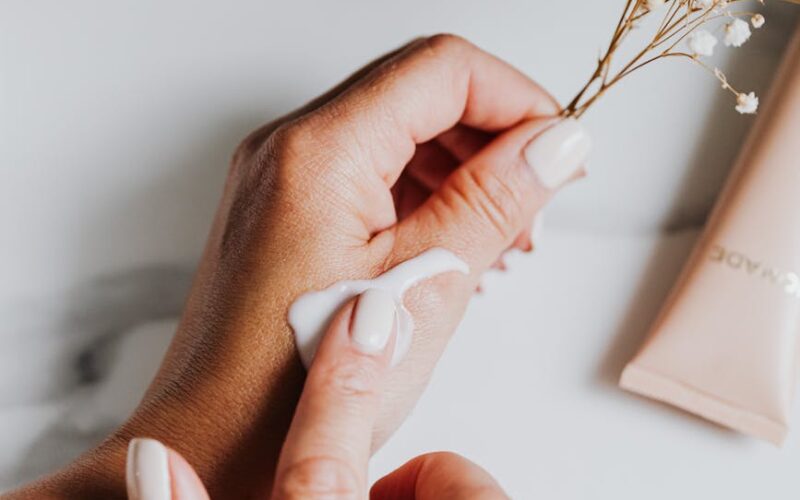 person holding white flower while applying lotion