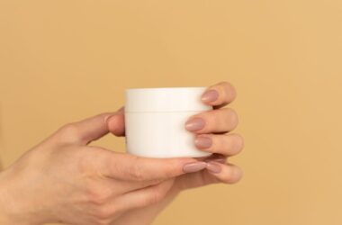 person holding white facial cream product