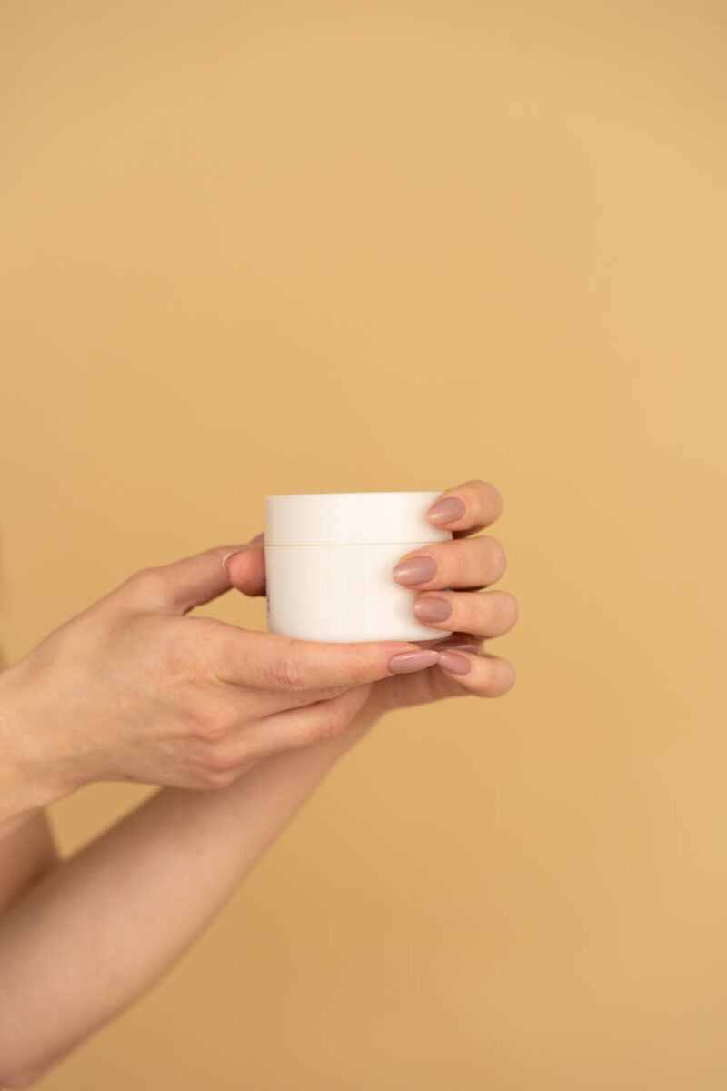 person holding white facial cream product