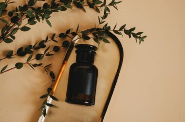 brown bottle with lid on wooden tray near green leaves