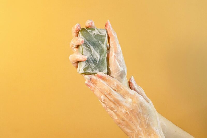 hands with soap bubbles holding a bar of soap