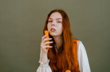 a woman in white long sleeves holding a carrot