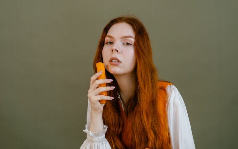 a woman in white long sleeves holding a carrot