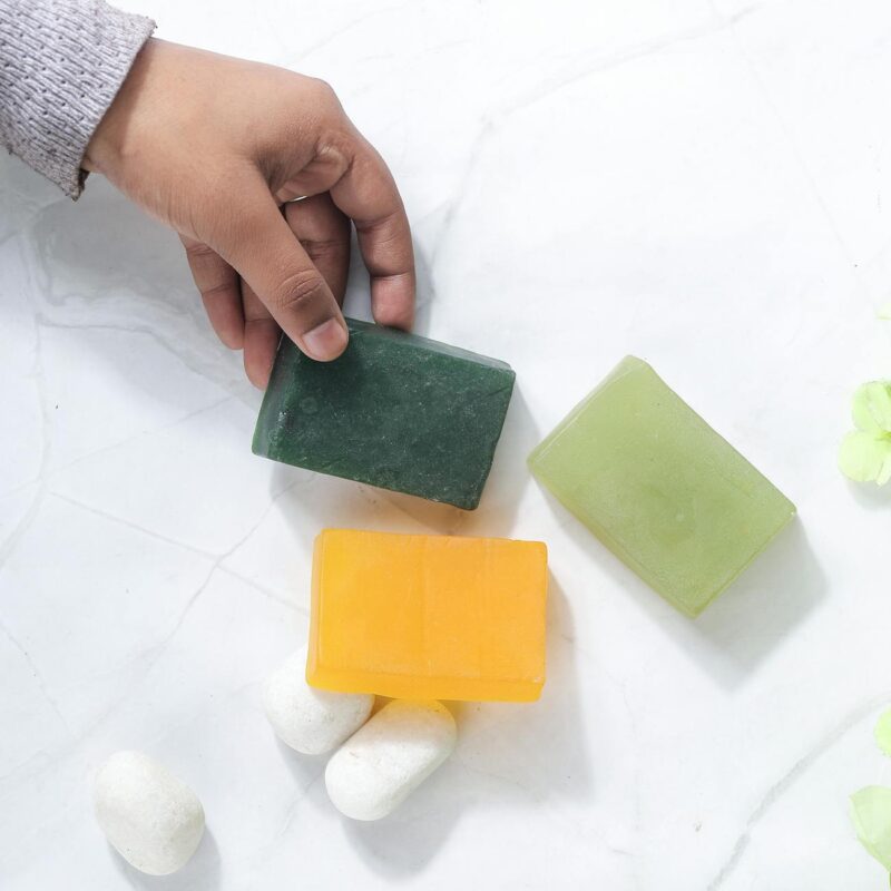 hand picking natural soap bars on marble surface