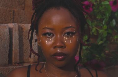 portrait of woman with glitter makeup against brick wall