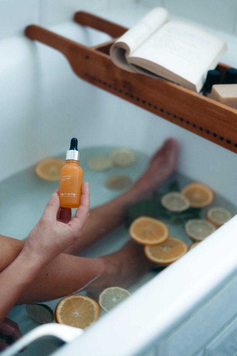 person holding orange and black plastic bottle