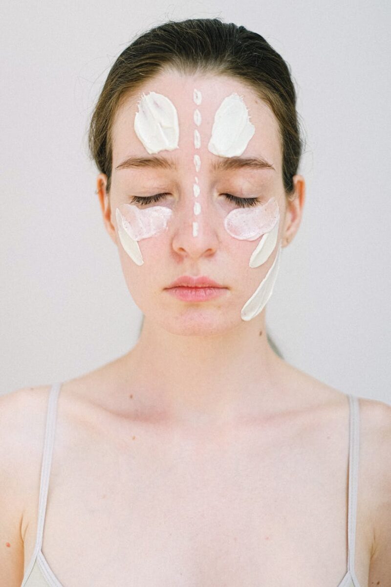 gentle young woman with white facial cream smears