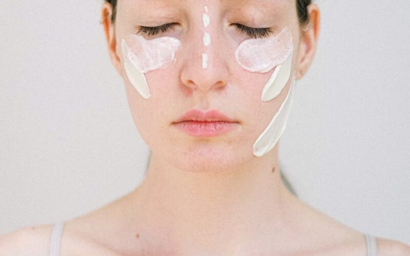 gentle young woman with white facial cream smears