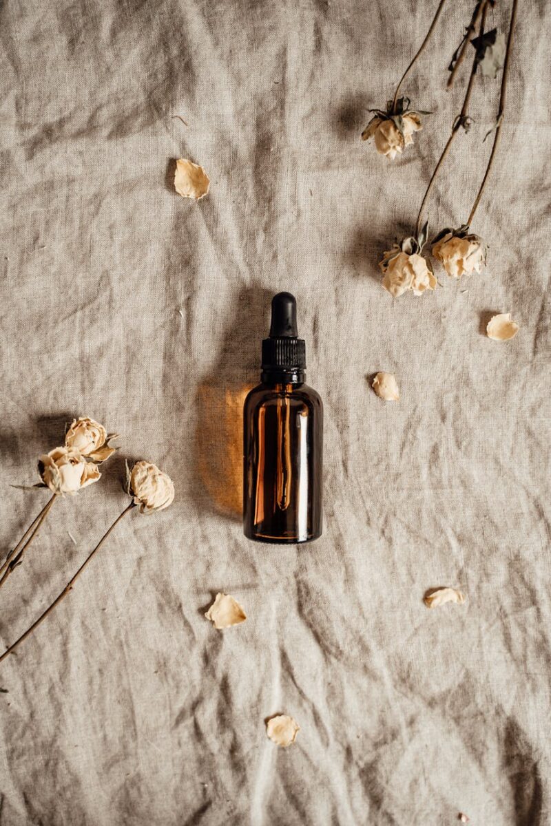 brown glass bottle with a pipette lying on fabric with flowers