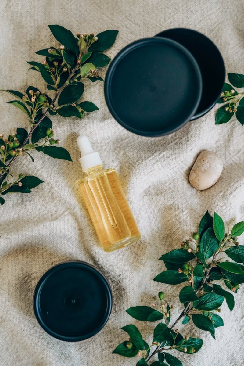 green leaves on branches near the glass serum bottle