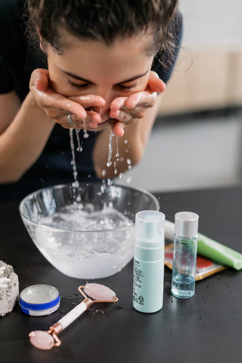 woman in black shirt washing her face with water