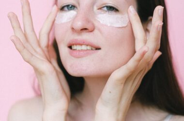 calm female applying cosmetic cream on face