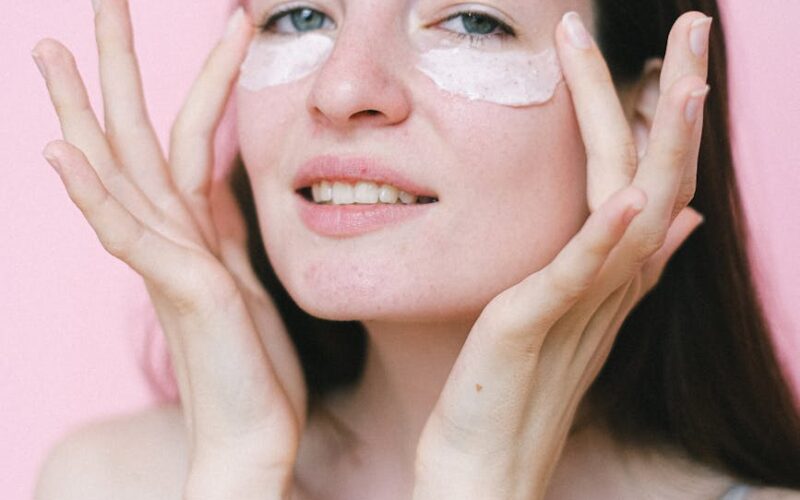 calm female applying cosmetic cream on face